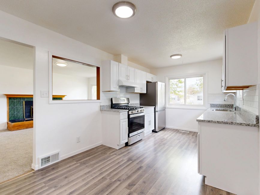 Bright, newly renovated kitchen featuring white cabinets, hardwood floors